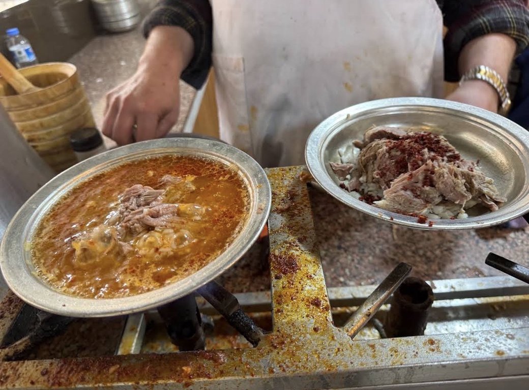Beyran cooking over a flame beside a portion of lamb and rice at Beyranci Mustafa in Gaziantep