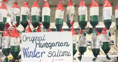 László’s packaged salami beneath a Winter salami sign at a Budapest market stall