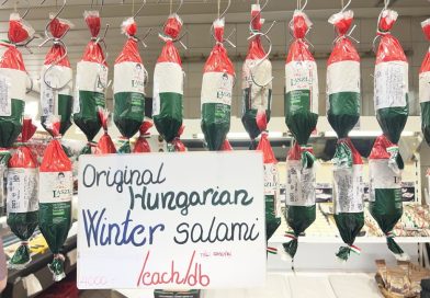 László’s packaged salami beneath a Winter salami sign at a Budapest market stall