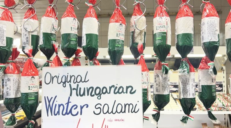 László’s packaged salami beneath a Winter salami sign at a Budapest market stall
