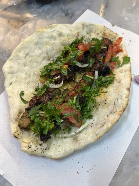 Liver skewers on tırnak pide with parsley, onion and tomato at Muhsinzade