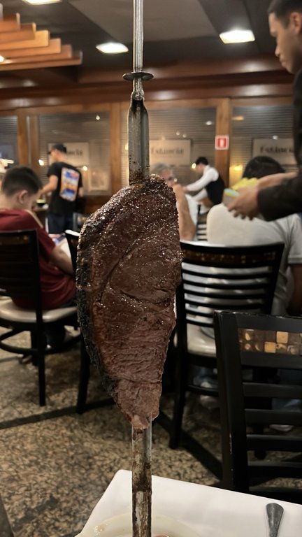 Meat on a skewer brought to the table at Churrascaria Estância