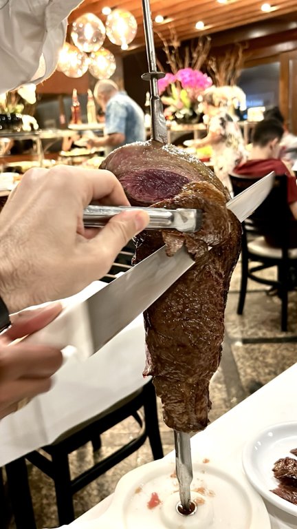 Meat sliced from a skewer at the table at Churrascaria Estância in São Paulo