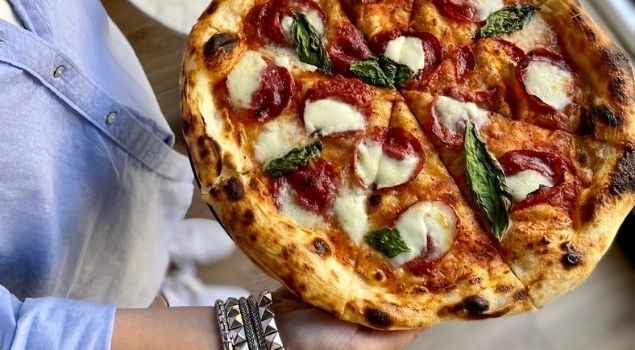 Pizza topped with sliced charcuterie, cheese and basil