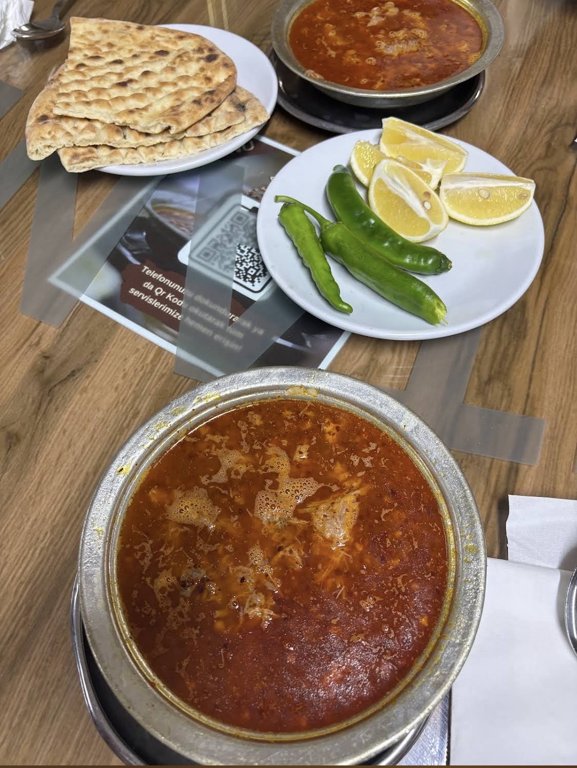 Two bowls of beyran with pide, lemon and green peppers at Metanet Lokantasi in Gaziantep
