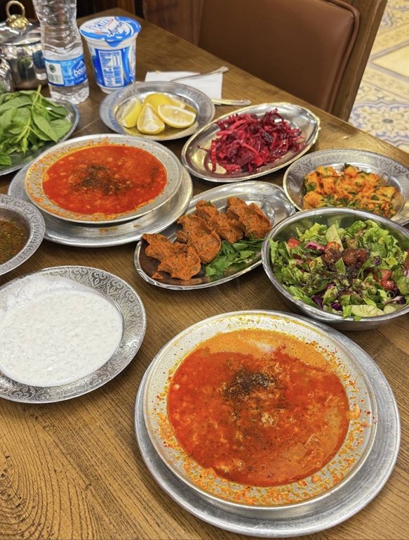 Two bowls of beyran with salads and side dishes at Kelebek in Gaziantep