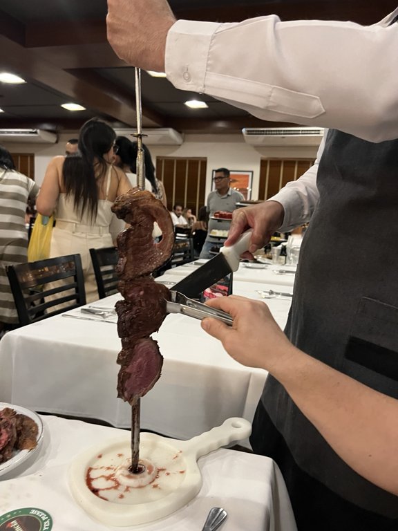 Waiter serving rodízio meat at Churrascaria Estância in São Paulo